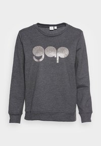Sudadera gris de cuello redondo hecha de un tejido suave con un corte relajado. Presenta el logo "gap" en glitter plateado en la parte frontal. Mangas largas y puños acanalados.