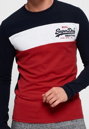 Langarm T-shirt met kleurvlakken in marineblauw, wit en rood. Tekst op de borst luidt "REAL SuperDry." Gemaakt van een zachte katoenmix.