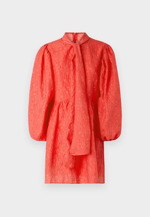 Koraļļu krāsas apgriezts kleitas modelis ar augstu kaklu, garām pūkainām piedurknēm un saitītes detaļu priekšpusē, ar savilktu vidukli un rāvējslēdzēju aizmugurē.