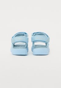 Blaue Sandalen mit verstellbaren Riemen, strukturiertem Fußbett und rutschfester Sohle. Die Rückansicht zeigt das Logo auf dem Riemen und ein sicheres Schnallendesign.