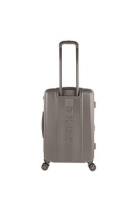 Maleta rígida en gris claro con textura acanalada vertical, dos asas de tiro, cuatro ruedas para movilidad y logo grabado en la parte frontal.