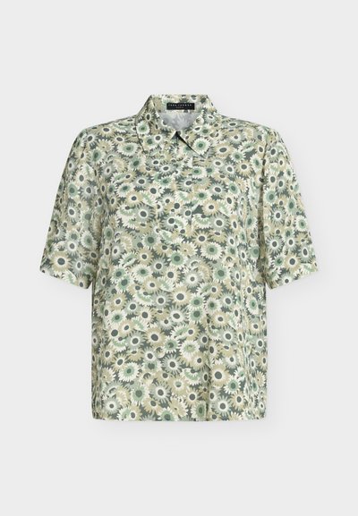 Short-sleeve collared blouse with button placket and green, beige, and white floral pattern on light fabric.