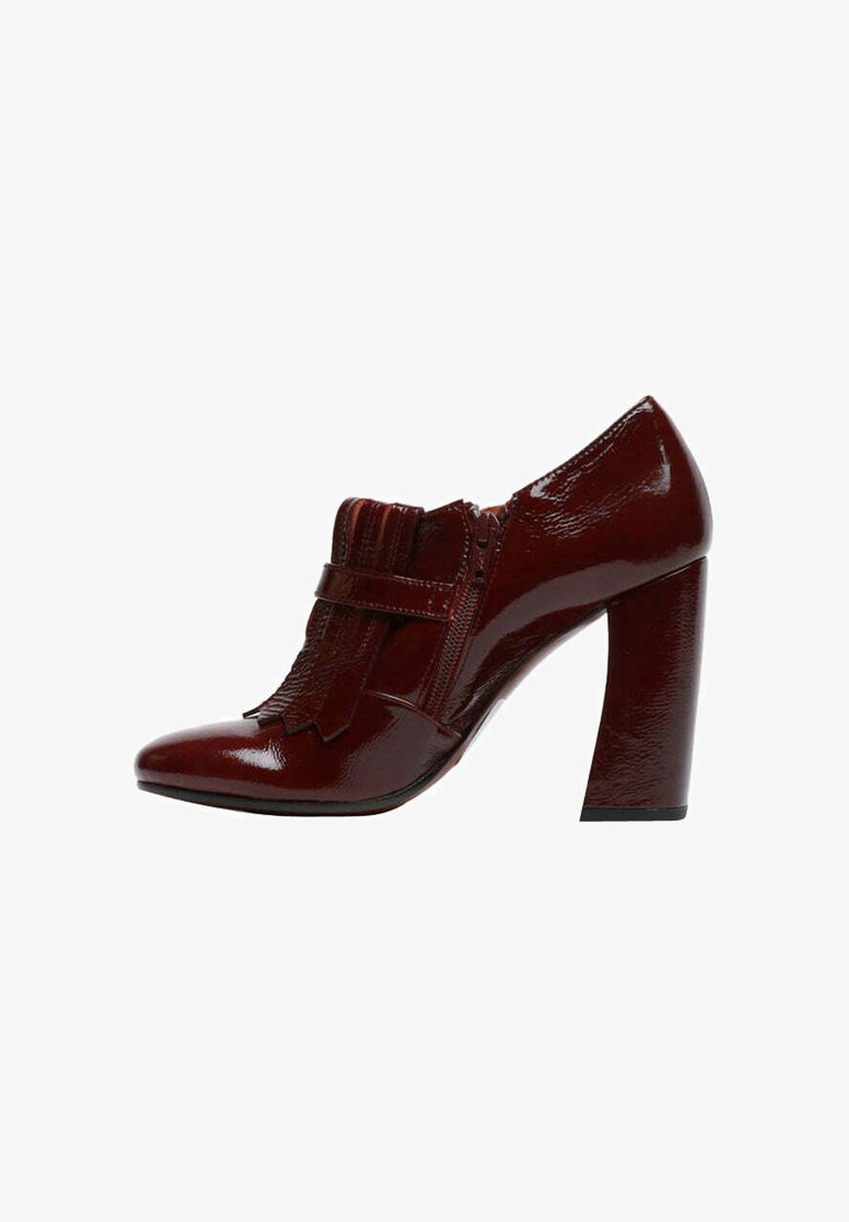 Scarpa con tacco alto in vernice rossa, punta appuntita, dettagli con frange e cerniera laterale. Presenta un tacco spesso e una texture liscia.