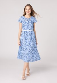 Abito midi floreale in tonalità blu, con maniche corte, scollatura a chiave e una cintura bianca. Lunghezza sotto il ginocchio con gonna fluente.