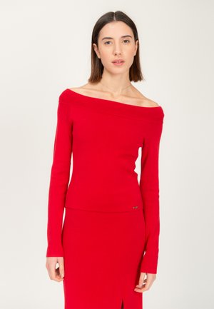 Rode off-shoulder top met geribbelde halslijn, aangesloten lange mouwen en een zachte textuur. Gecombineerd met een bijpassende rode rok, met een zijsplit.