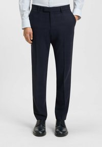 Marinblå skräddarsydda byxor med rutig mönster, flat framsida, sidfickor och bälteshällor, kombinerat med svarta snörskor.