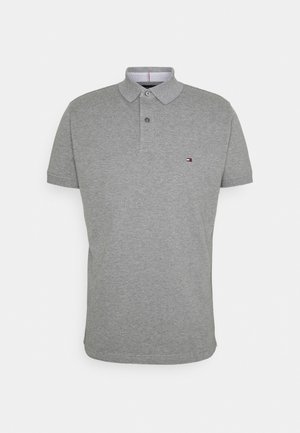 Polo gris à manches courtes avec patte de boutonnage à deux boutons et petit logo Tommy Hilfiger sur le côté gauche de la poitrine.