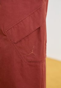 Shorts cargo în nuanță de burgundă, cu o mare bucată laterală și un logo Jumpman brodat. Fabricate dintr-un material ușor, neted, cu un finisaj curat.