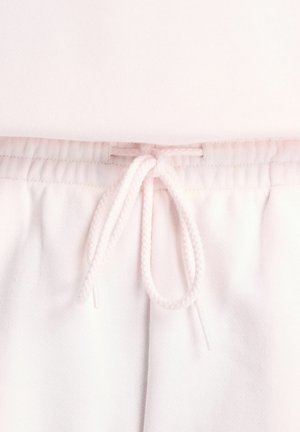 Nahaufnahme von rosafarbenen Sweatpants mit elastischem Bund und mittig vorn gebundenen Kordelschlaufen.