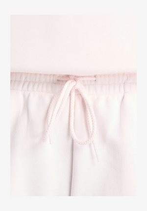 Close-up van lichtroze joggingbroek met elastische tailleband en gestrikte trekkoorden aan de voorzijde.