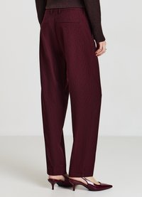 Pantalon bordeaux à fines rayures avec une coupe droite, passants de ceinture et poches arrière, associé à des escarpins bordeaux à bouts pointus.