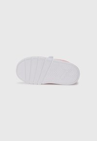 Semelle de sneaker pour enfant en caoutchouc blanc avec un motif de semelle texturé et un logo de marque en relief, présentée par le dessous sur un fond blanc uni.