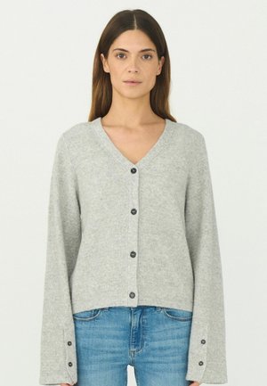 Grå v-ringad cardigan med strukturerad stickning, knappframslutning och långa, vida ärmar med knappdetaljer. Bärs över blå jeans.