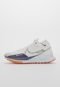 Chaussure de trail running Nike blanche et orange avec tige en Gore-Tex, semelle intermédiaire marbrée et semelle texturée pour une utilisation en extérieur.