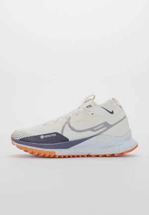 Chaussure de trail running Nike blanche et orange avec tige en Gore-Tex, semelle intermédiaire marbrée et semelle texturée pour une utilisation en extérieur.