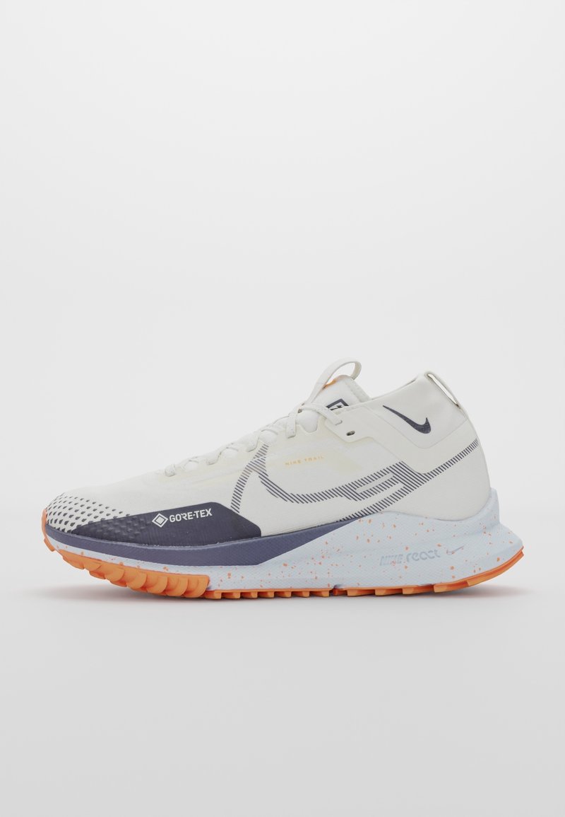Chaussure de trail running Nike blanche et orange avec tige en Gore-Tex, semelle intermédiaire marbrée et semelle texturée pour une utilisation en extérieur.