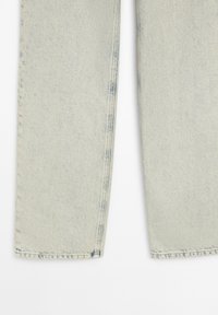 Jambes de jean en denim bleu clair avec des ourlets droits et des détails subtilement délavés près des coutures et des poignets.