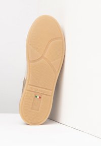 Semelle de chaussure en caoutchouc beige avec une surface texturée, portant le nom de la marque "NeroGiardini" et la taille "37" gravés. Pays d'origine indiqué.
