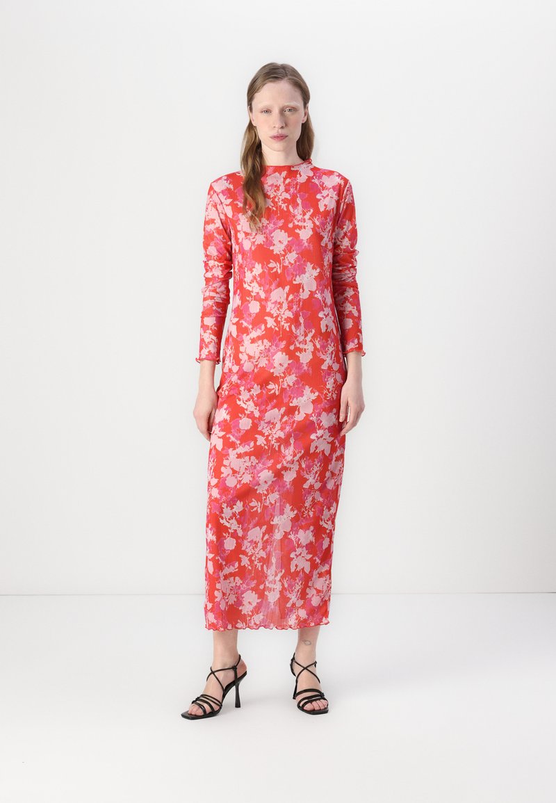 Abito lungo maxi floreale rosso con maniche lunghe, caratterizzato da motivi di fiori rosa e bianchi. Realizzato in tessuto leggero, con una consistenza liscia.