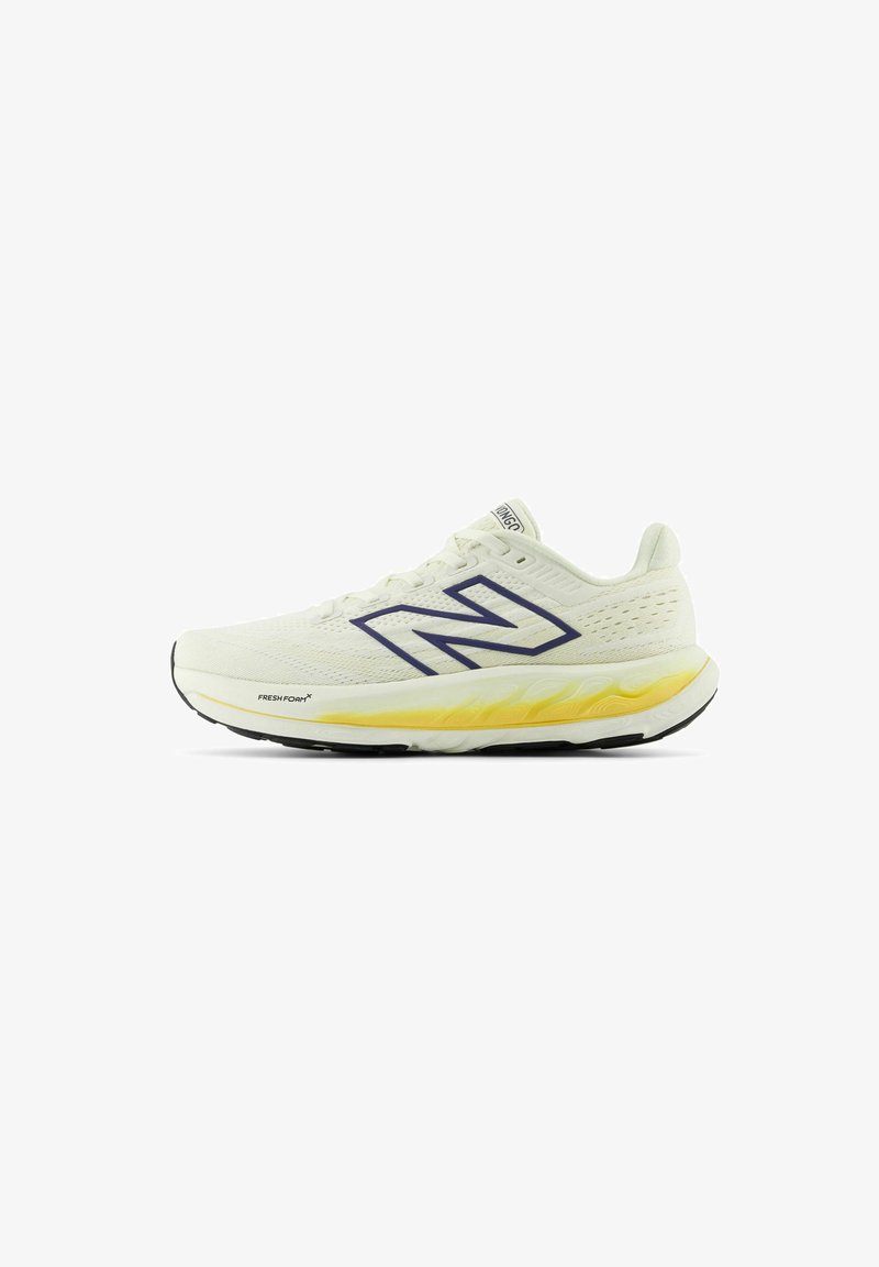 Miestne bežecké topánky New Balance v svetlej krémovej farbe s priedušným sieťovaným vrchom. Medzi funkcie patrí výrazné tmavomodré logo a žlté odpruženie.