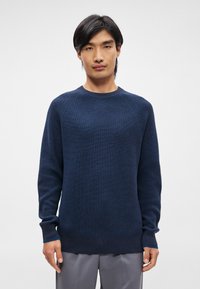 Pulover cu tricot cu dungi, de culoare bleumarin, cu guler rotund și mâneci lungi, având un material texturat și un tiv drept.