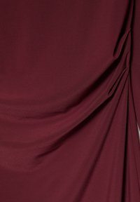 Material bordo cu suprafață texturată, cu drapaje adunate și pliuri subtile. Designul evidențiază profunzimea și mișcarea.