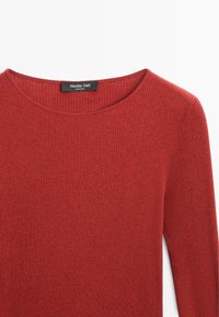 Top lungo a maniche lunghe rosso a coste con scollatura a barca. Realizzato in materiale morbido. Presenta un'etichetta che indica il marchio e il paese di origine.