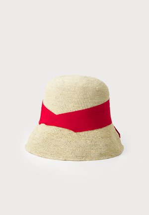 Sombrero de paja con una amplia banda de tela roja alrededor de la corona. Textura Beige y forma redondeada con una ligera curva hacia arriba en el ala.