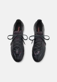 Zwarte sportieve schoenen met een strakke vormgeving, een gestructureerde bovenkant en een grijze gaas tong. Voorzien van zwarte veters en rode logo-accenten op de binnenzool.