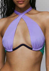 Paarse en groene bikini-top met een driehoekige vorm, kruislingse ontwerpen, en contrasterende marineblauwe bies langs de randen en onderband.