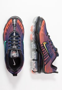 Nike Air Max-skor med en texturerad mörkblå ovandel, orange och lila gradiantdetaljer samt klara luftdämpning sålar.