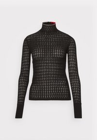 Pull à col roulé noir présentant un motif zigzag texturé, une coupe ajustée, des manches longues et un discret accent rouge au niveau du col.