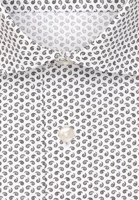 Camicia bianca con un motivo ripetitivo di piccole spirali scure. Presenta un colletto classico e una chiusura con bottone in perla sul davanti.