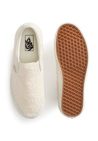 Béžové fuzzy nazouvací boty s texturovaným svrškem, bílou gumovou mezipodešví a hnědou vzorovanou podešví. Logo Vans je viditelné uvnitř.
