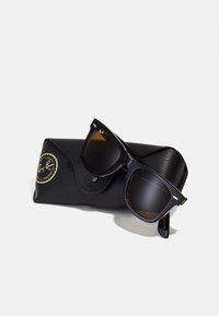 Black Ray-Ban sunglasses with dark lenses, square frame design, and metal accents, resting on a textured black leather case with logo.