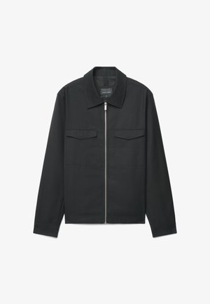 Schwarze Reißverschlussjacke aus glattem Stoff, mit spitzem Kragen, zwei Fronttaschen und langen Ärmeln mit geknöpften Manschetten.