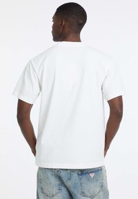 Witte korte mouwen t-shirt van katoen, met een ronde hals en een relaxte pasvorm. Draag het met lichtblauwe, vervaagde cargobroeken.