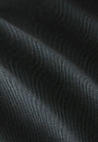 Tejido negro con una superficie texturizada y acanalada. El material parece suave, con líneas horizontales visibles y un ligero brillo.