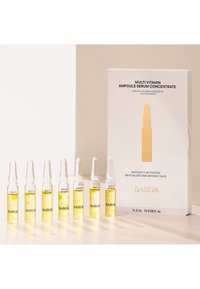 Babor Multi Vitamin Ampoule Serum Concentrate-setet innehåller sju glasampuller med gul vätska, presenterat i en vit låda som visar produktdetaljer.