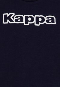 Tricou din bumbac bleu marin, având un mare logo alb "Kappa" imprimat pe față. Țesătura pare netedă și ușor texturată.