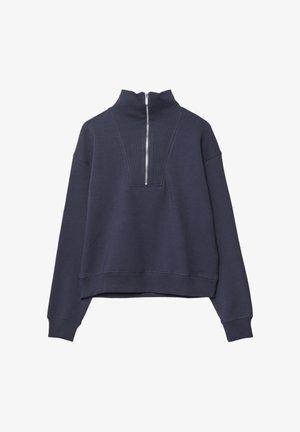 Námořnická modrá zkrácená mikina s vysokým límcem a polo zipem vpředu. Materiál vypadá měkce a má hladkou texturu.