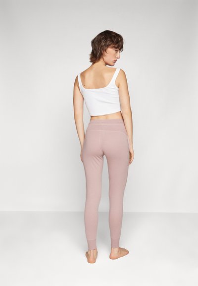 Vaaleanpunaiset legginsit, joissa on kapea malli, nilkkapituus ja joustava vyötärö. Valkoinen ilmanhiha crop-top, jossa on neliömainen selkädesign.