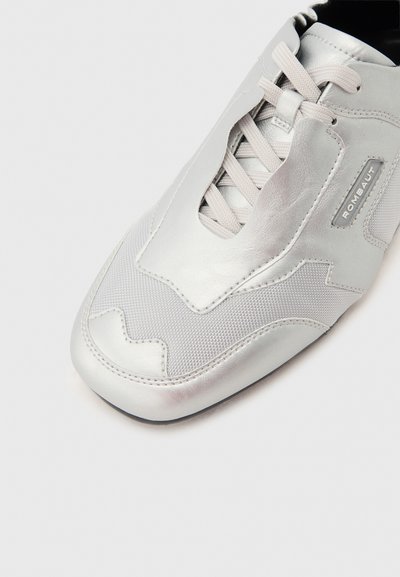 Αθλητικό παπούτσι σε ανοιχτό γκρι δέρμα και δίχτυ με μπεζ κορδόνια και ετικέτα "ROMBAUT" στο πλάι, εμφανιζόμενο από κοντινή λήψη από πάνω.