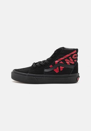 Czarne sneakersy Vans za kostkę z czarnymi sznurowadłami i czerwonym logo Vans po boku, płaska podeszwa i wyściełany kołnierz na kostkę.