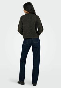 Grauer Strickpullover mit cropped Passform, kombiniert mit dunkelblauen geraden Jeans. Verfügt über einen schlichten Rundhalsausschnitt und sichtbare Nahtdetails.