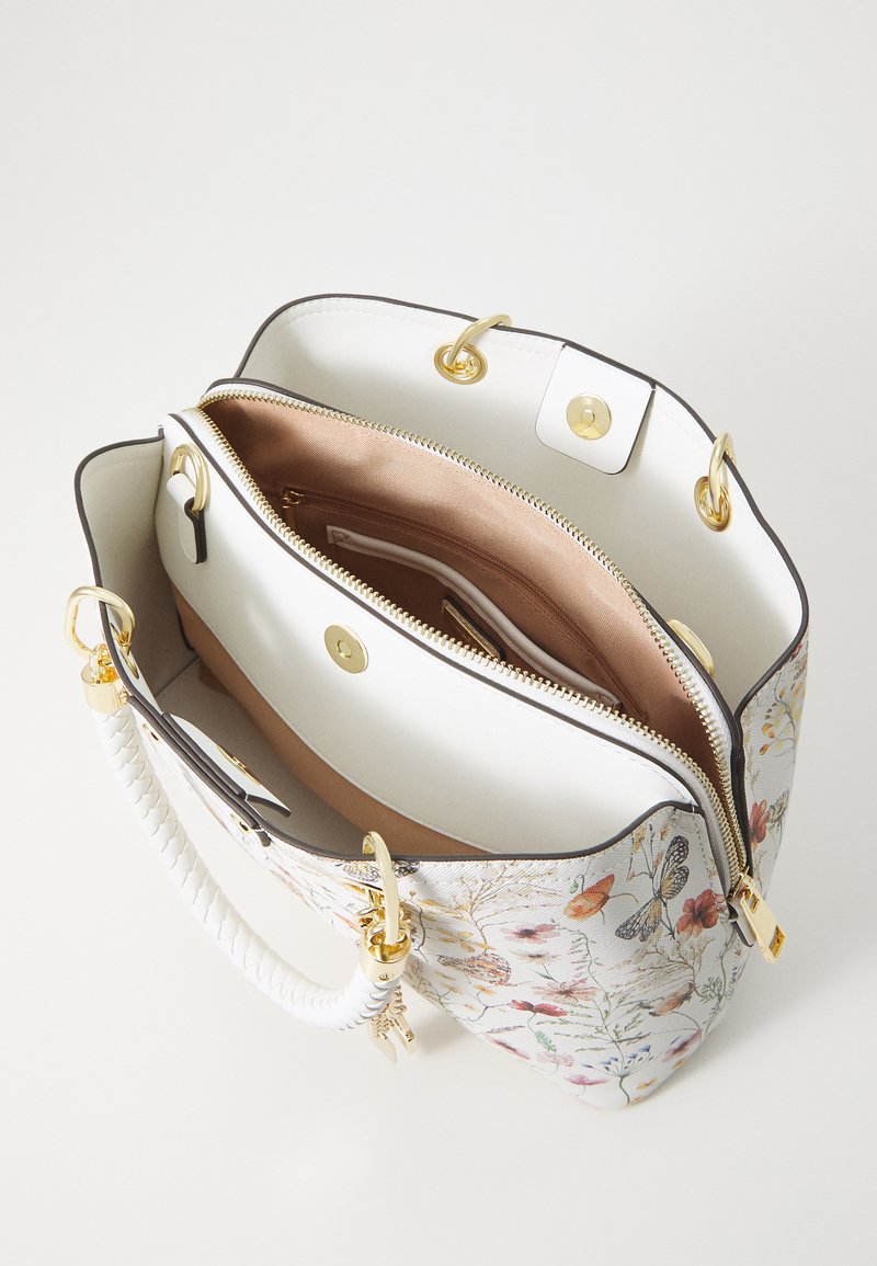 Sac à main blanc avec un motif floral, quincaillerie dorée et une poignée tressée. L'intérieur comporte un compartiment zippé et une doublure lisse.