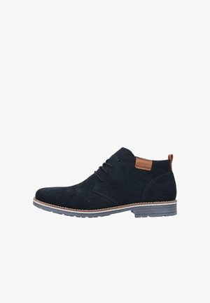 Botines de ante azul oscuro con cierre de cordones, acento marrón en el tacón y suela de color claro. Presenta una superficie texturizada.