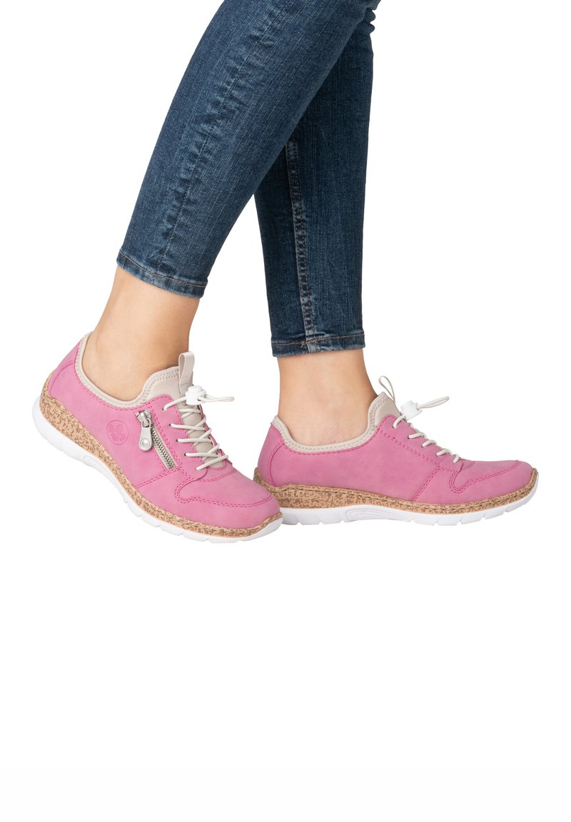 Baskets de sport roses avec une semelle en liège texturée, un design à lacets et une fermeture éclair sur le côté. Matériau supérieur lisse avec des accents gris clair contrastants.