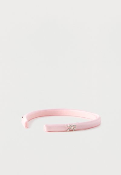 Λεπτή ροζ σατέν κορδέλα για το κεφάλι με ένα μικρό ασημένιο διακοσμητικό γράμμα "R" από στρας στη μία πλευρά, εμφανίζεται σε λευκό φόντο.