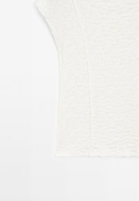 Witte textuurtop met een gekrulde oppervlakte. Heeft korte mouwen en een rechte snit, met zichtbare naden langs de zijkant.